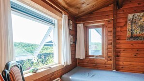 Ein gemütlicher Holzblockraum mit Bett, kleinem Tisch und Stuhl.