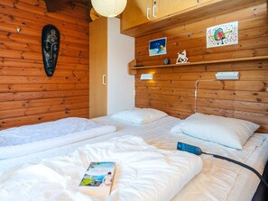 A wooden cabin room with two beds, a wall-mounted mask, and children's artwork. - 5 Person Holiday Home in Fano (Fano)