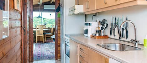 A compact kitchen with wooden cabinets, a built-in microwave, and a sink.