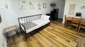 Huoneessa on sänky, televisio, ruokapöytä ja pieni keittiöalue.
