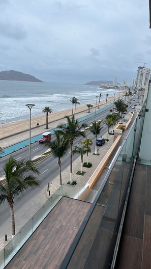 A coastal road with palm trees, a beach, and buildings in the background. - Charming 2-bedroom apartment on El Malecon with AC in Mazatlán. Great ocean view (Mazatlán)