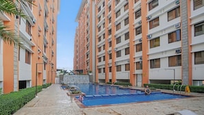 Un edificio residencial de varios pisos, con un patio central y una piscina, y un camino de piedra.