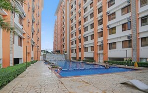 A residential building with multiple floors, a central courtyard with a swimming pool, and a stone pathway. - Serene Stay at Paseo Verde (Las Piñas)