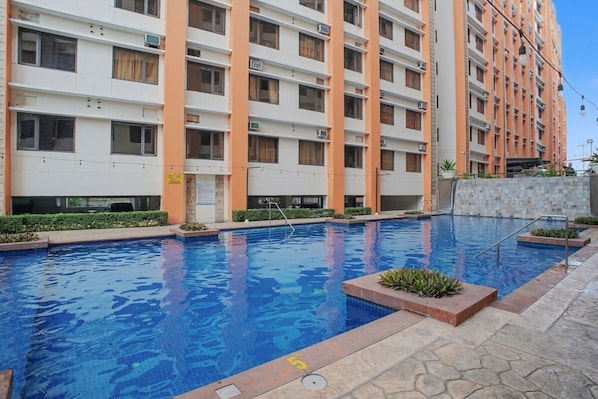 A multi-story residential building with a swimming pool. - Serene Stay at Paseo Verde (Las Piñas)