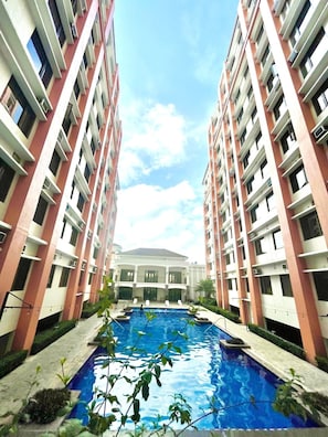 A multi-story residential building with a central swimming pool surrounded by greenery. - Serene Stay at Paseo Verde (Las Piñas)