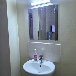 A bathroom with a white sink, a mirror, and a bottle of Eriprime hand sanitizer. - Cutie Suites TRM | Fast Wi-Fi • Netflix • Parking (Nairobi)