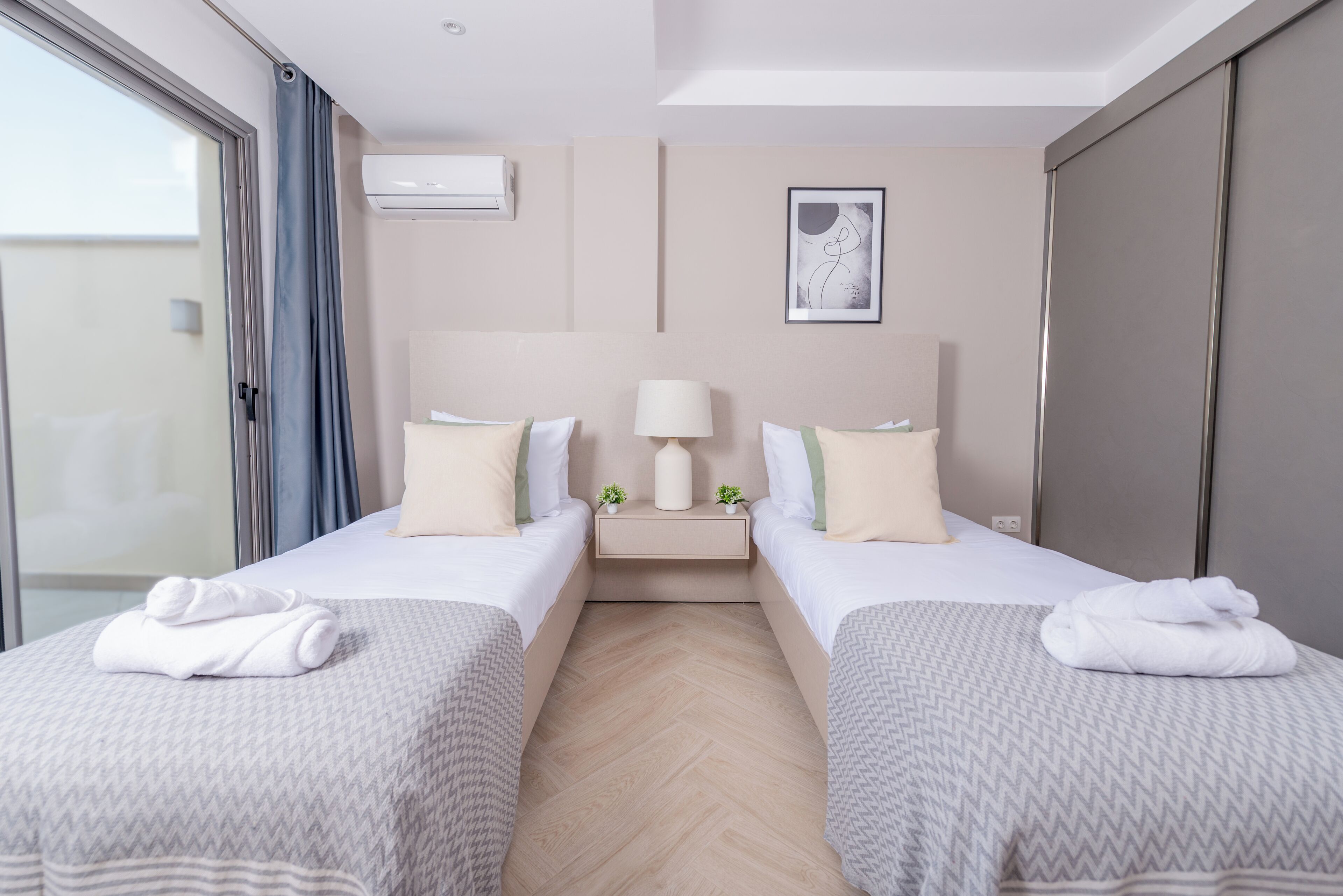 A hotel room with two beds, a nightstand with a lamp, and a picture on the wall.