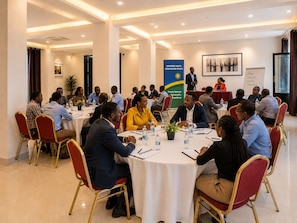A conference room with round tables, chairs, and attendees engaged in a meeting.