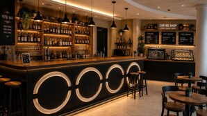 Zona de bar con mostrador, estanterías llenas de botellas y una sección de cafetería con paneles de menú.