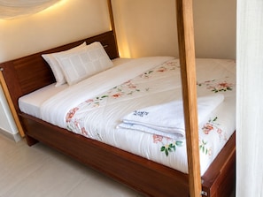 A single bed with a wooden frame, white bedding, and a floral-patterned duvet.