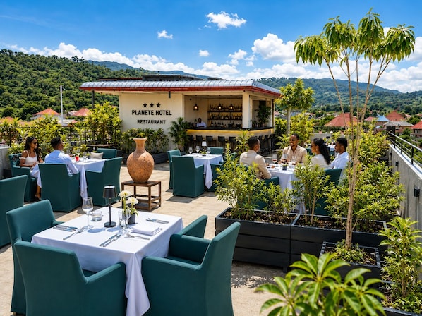 An outdoor dining area with tables and chairs, a large vase centerpiece, and a restaurant sign.