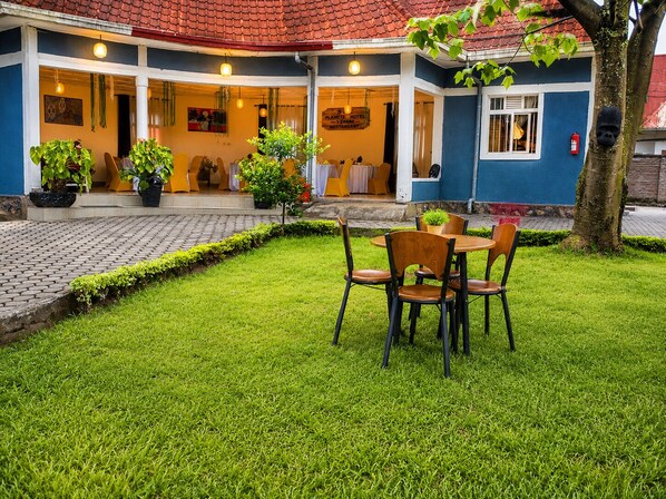 Un hôtel doté d’un espace extérieur couvert avec des sièges, de plantes en pot et d’un extincteur.