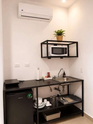 A compact kitchenette with a microwave, sink, and Hisense refrigerator.