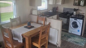 Una cocina compacta con una mesa de comedor, sillas, lavadora y estufa.