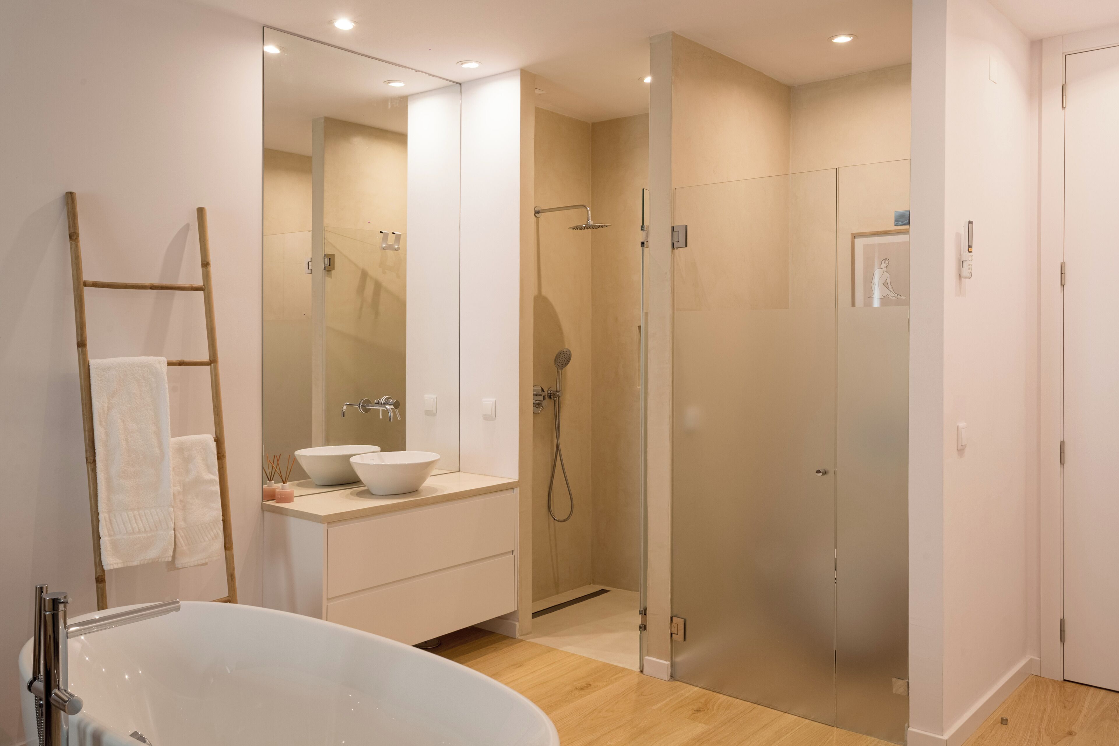 Une salle de bain moderne avec une baignoire sur pieds, une douche à parois de verre et un meuble-lavabo doté d’un grand miroir.