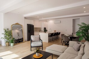 Ein modernes Wohnzimmer mit Sofa, Couchtisch und Essbereich mit Stühlen und Tisch.