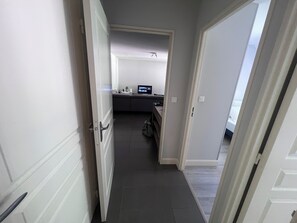 Ein schmaler Flur, der in einen Raum mit einem Bett und einem Schreibtisch führt.