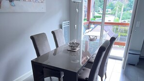Ett modernt matområde med ett glasbord och stolar, en dekorativ skål och utsikt över omgivningen.