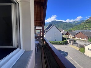 Ein Balkon mit Blick auf eine Straße, Gebäude und Berge.