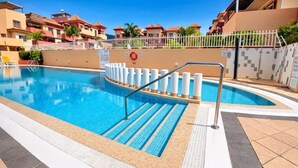 Una piscina con barandilla de seguridad, solárium con baldosas y un flotador salvavidas.