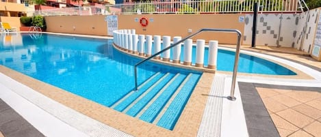 A swimming pool with a safety railing, tiled deck, and a lifebuoy.