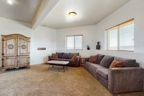 A spacious living room with a large sofa, a coffee table, and a wooden cabinet. - Big Bear Cabin | Sleeps 32, Near Marina, Lake Views, AC, Log Cabin! (Garden City)