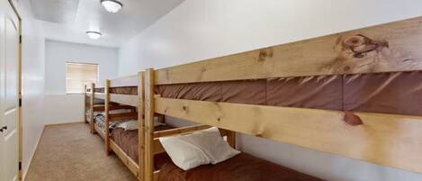 A room with bunk beds, a door, and a window with blinds.