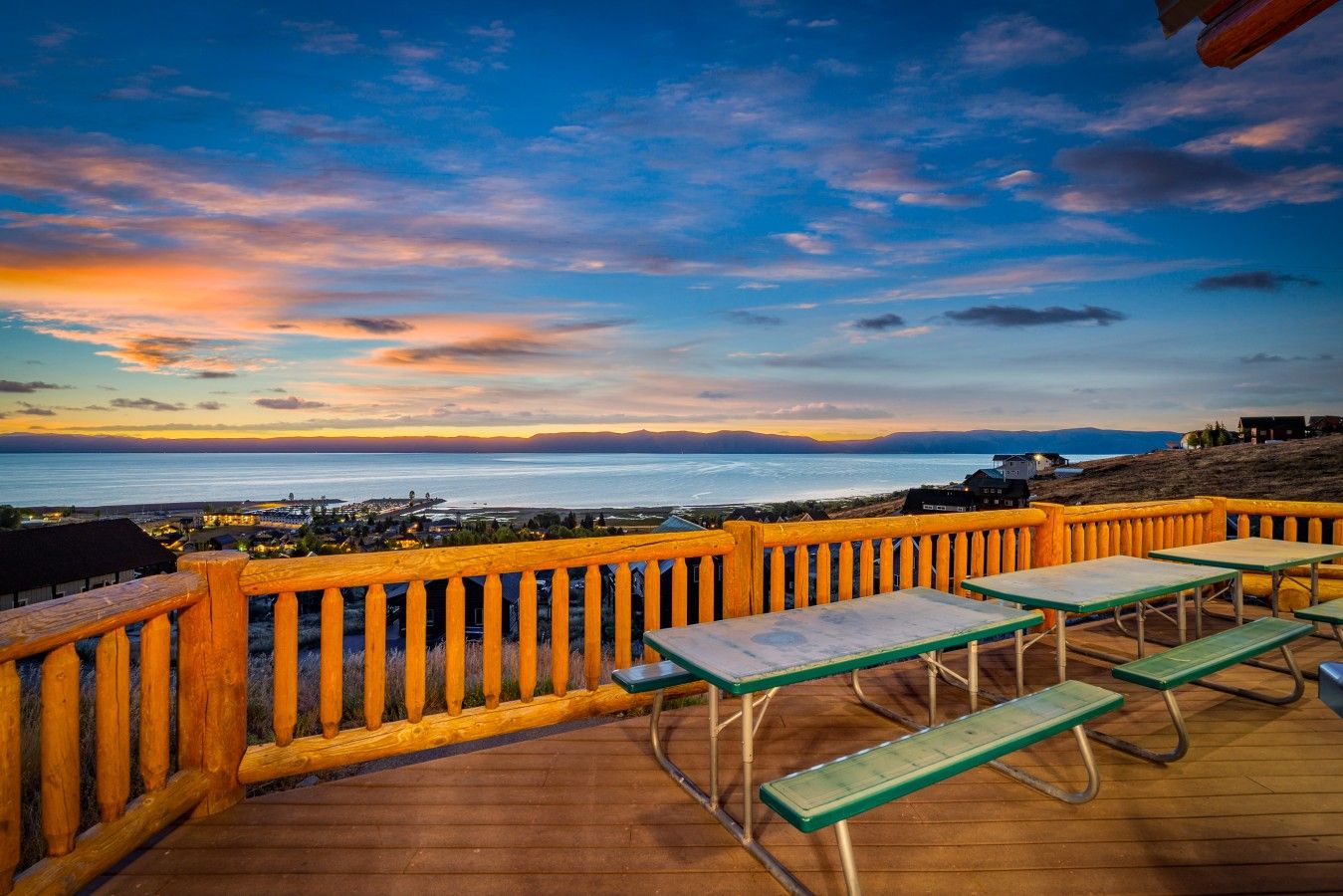 Une terrasse en bois avec des tables de pique-nique, offrant une vue sur la côte.