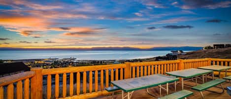 A wooden deck with picnic tables overlooking a coastal view.