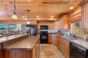 A kitchen with wooden cabinets, a granite countertop, a built-in oven, and a dishwasher. - Big Bear Cabin | Sleeps 32, Near Marina, Lake Views, AC, Log Cabin! (Garden City)