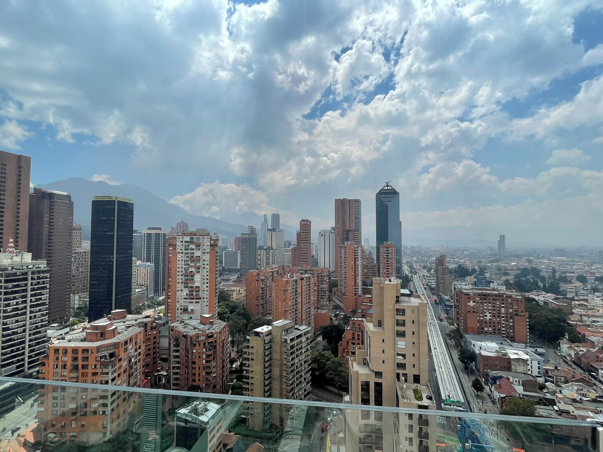 A cityscape with high-rise buildings, a mountain in the background, and a clear sky.
