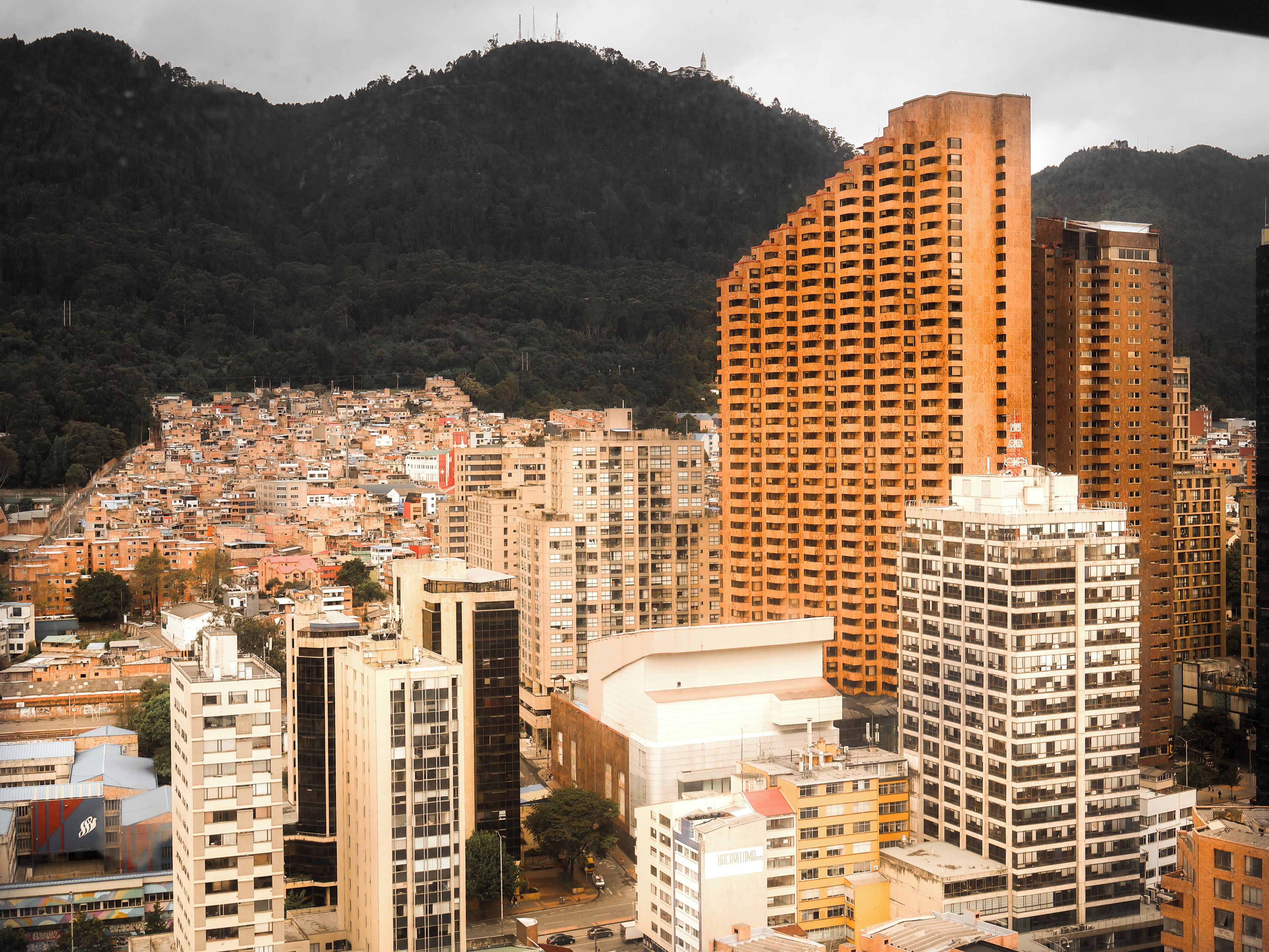 A cityscape with high-rise buildings, a dense urban area, and a mountainous backdrop.