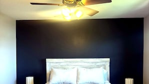 Ein Schlafzimmer mit einem Bett, einem Deckenventilator und Nachttischlampen.