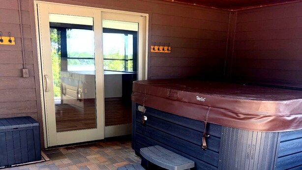 Ein Whirlpoolbereich mit Holzboden, einer Schiebetür aus Glas und einer Terrasse mit Backsteinmuster.