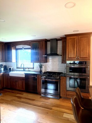 A kitchen with wooden cabinets, a stainless steel range, and a double oven.