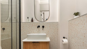 Un bagno con un armadietto in legno, un lavabo bianco, uno specchio e un water.