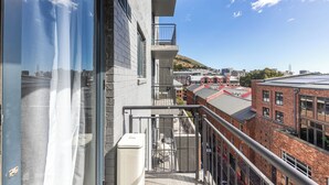 Un edificio alto con un balcone che si affaccia su un paesaggio urbano, con edifici in mattoni e cielo sereno.