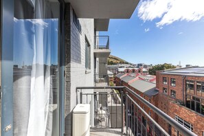 Un edificio alto con balcón que ofrece vistas a un paisaje urbano, con edificios de ladrillo y cielo despejado.