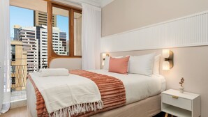 Camera d'albergo con un letto, un comodino, una finestra vista edifici e uno skyline urbano.