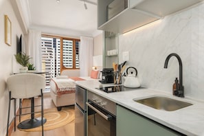 A modern kitchen with a large window, a built-in oven, and a stainless steel sink. - Charlie and the Chairman | CBD Retreat | Balcony (Cape Town)
