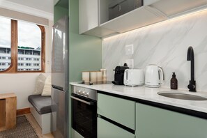 A compact kitchen with a built-in oven, a coffee maker, and a sink. - Charlie and the Chairman | Contemporary Suite (Cape Town)