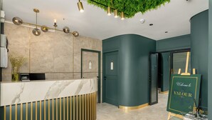 Een receptie met een marmeren balie, een groene wand en een welkomstbord.
