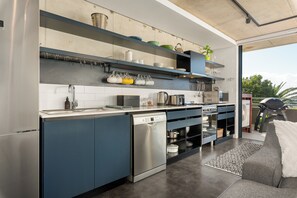 A modern kitchen with built-in appliances, a dishwasher, and a countertop with various kitchen items. - Skyline Escape | Views, Pool and Braai (Cape Town)