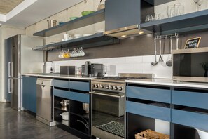 A modern kitchen with stainless steel appliances, blue cabinetry, and a chalkboard sign. - Skyline Escape | Views, Pool and Braai (Cape Town)