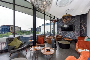 Eine moderne Lounge mit Ledersesseln, einem Kamin und großen Fenstern mit Blick auf die Stadt.