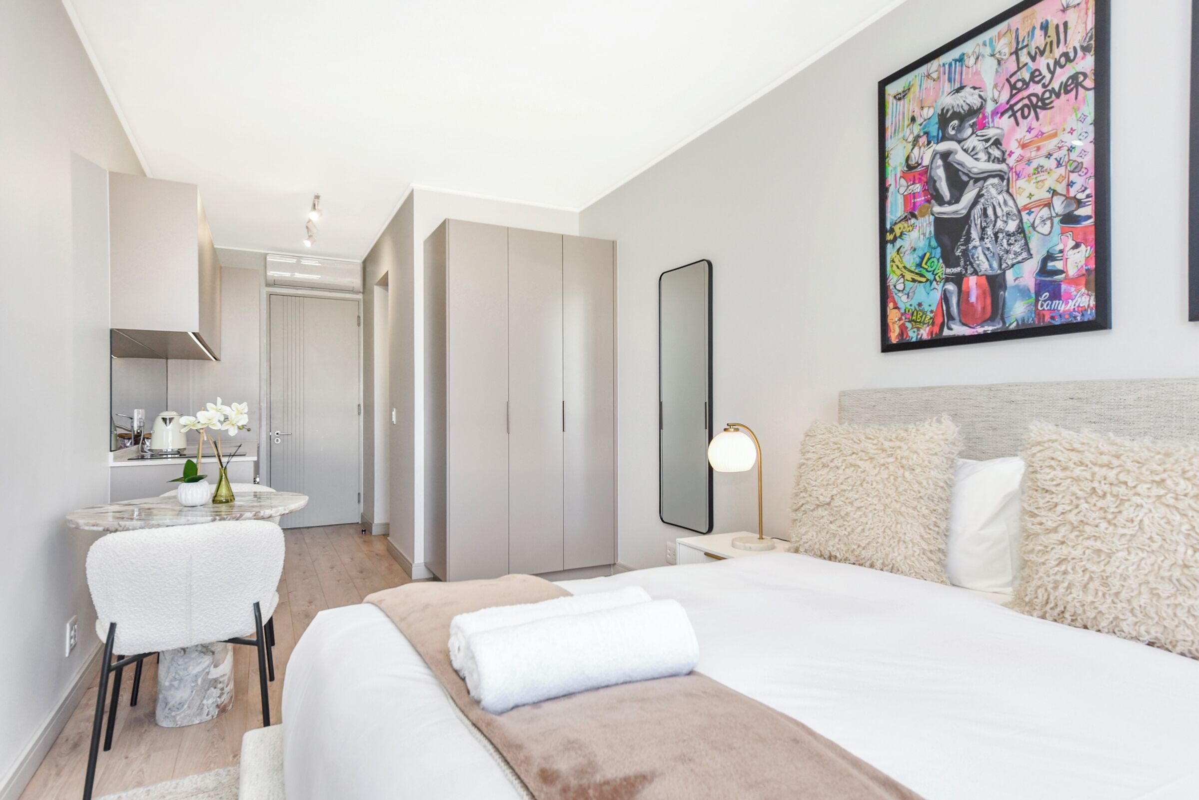 Una camera d'albergo moderna con un letto, una scrivania, uno specchio e un quadro appeso al muro.