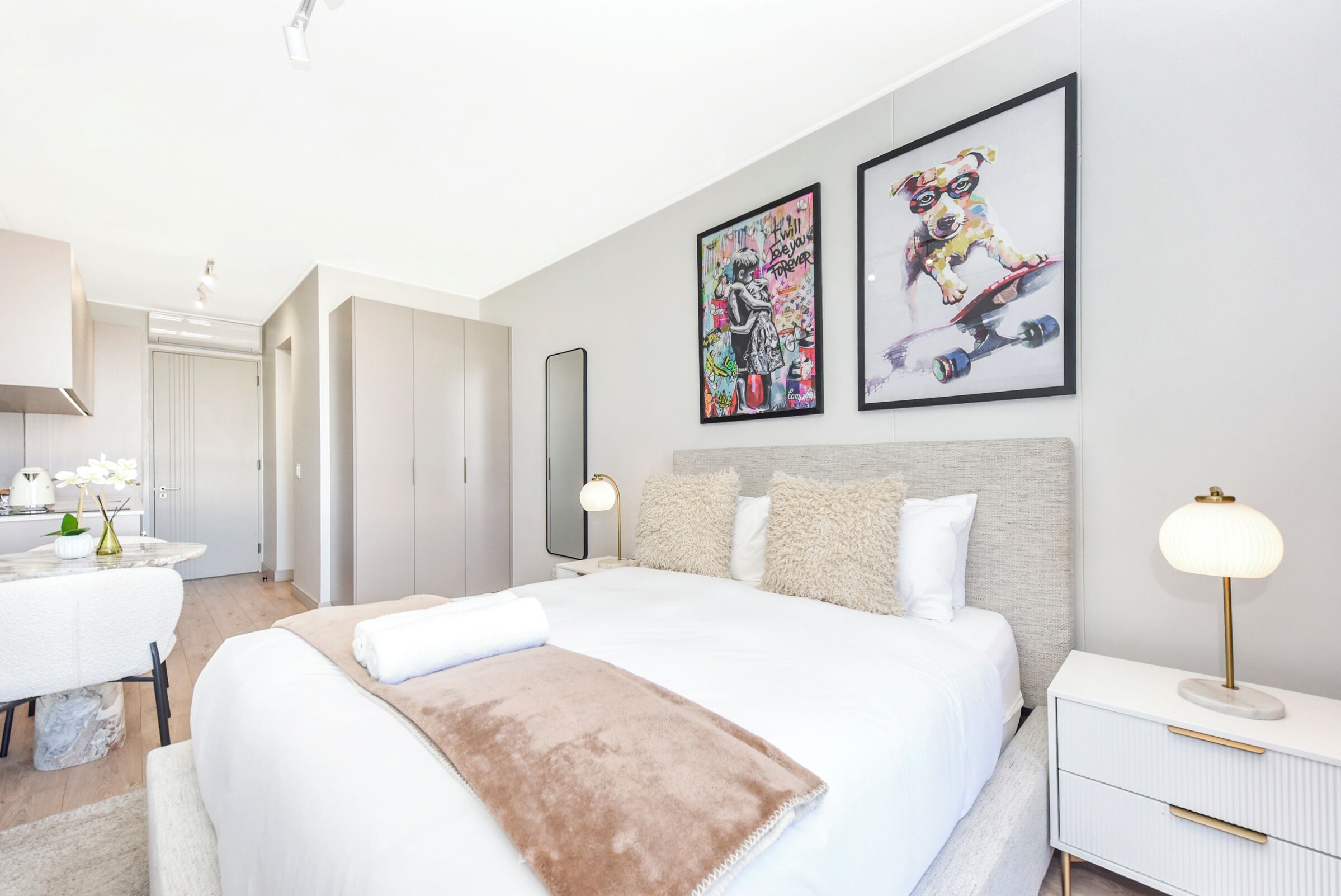 Une chambre d’hôtel moderne, dotée d’un grand lit, de tables de chevet, d’un bureau et d’œuvres d’art accrochées aux murs.