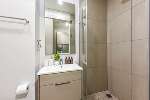 Ein modernes Badezimmer mit einer Glasdusche, einem weißen Waschbecken und einem Spiegel darüber.