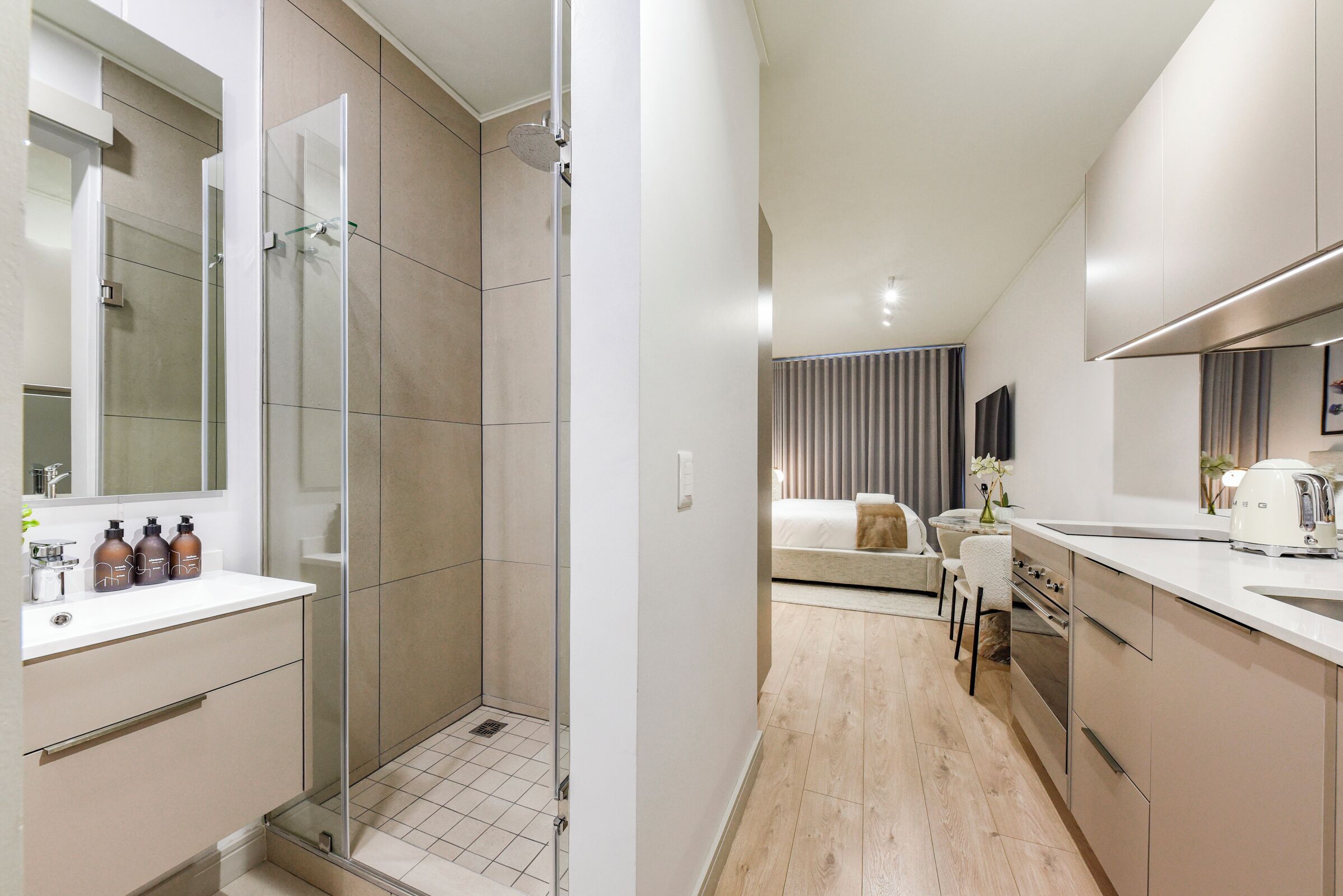 Une salle de bain moderne avec une douche à parois de verre, un lavabo blanc et un miroir.