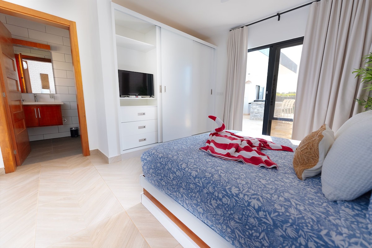 Ein Schlafzimmer mit Bett, Fernseher, Kleiderschrank und einer Schiebetür zum Balkon.